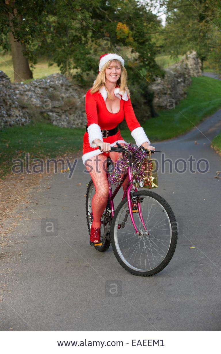 woman-in-santa-outfit-riding-a-decorated-bicycle-on-a-country-lane-EAEEM1.jpg